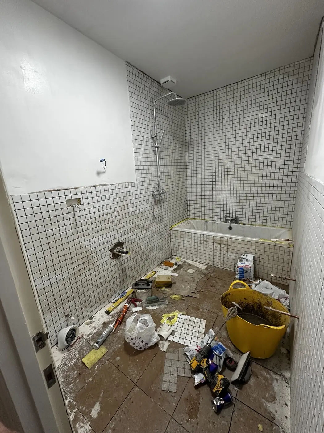 White mosaic bathroom tiles and shower being installed