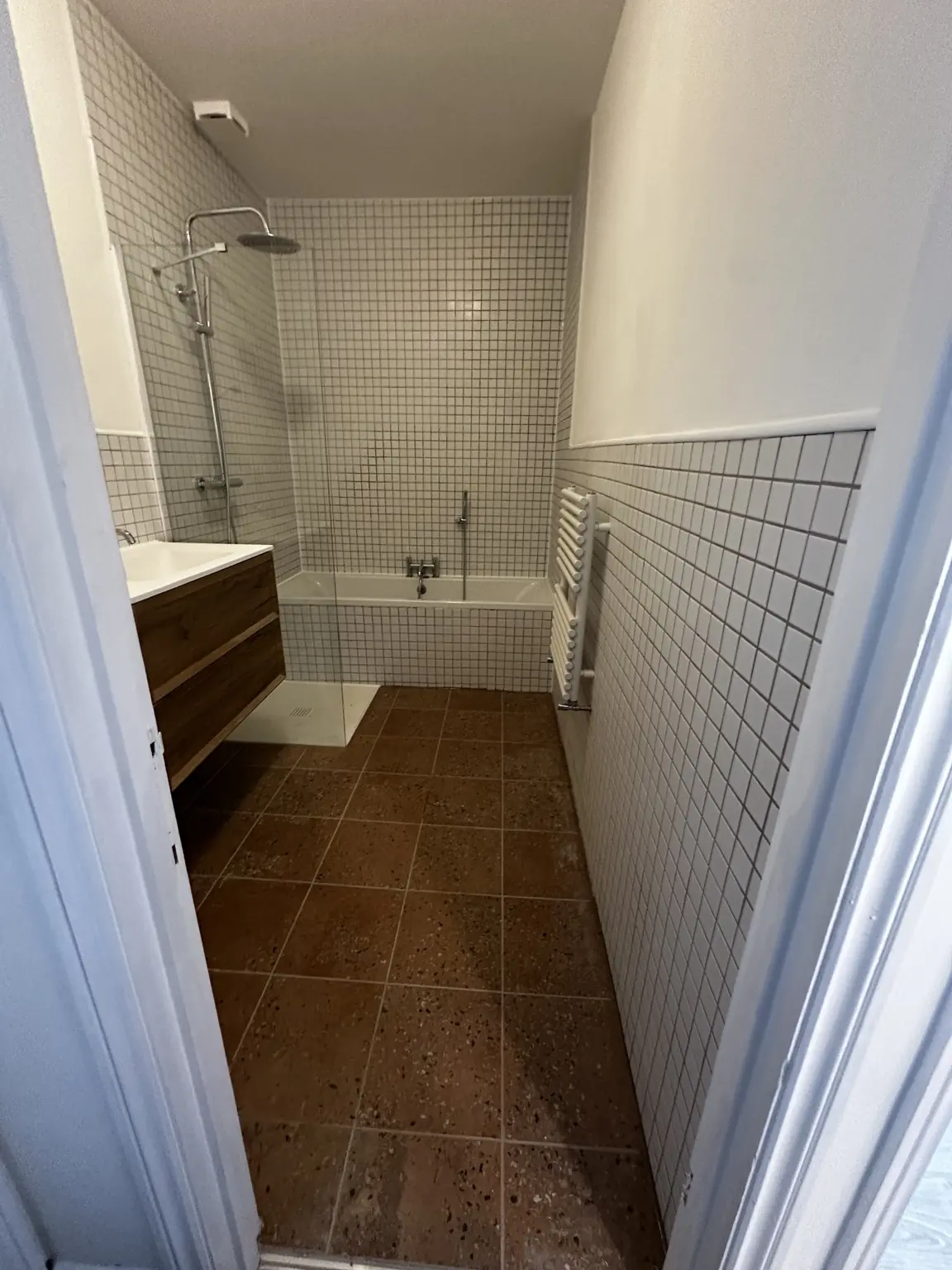 Completed bathroom viewed from the doorway with bath, shower and tiled walls